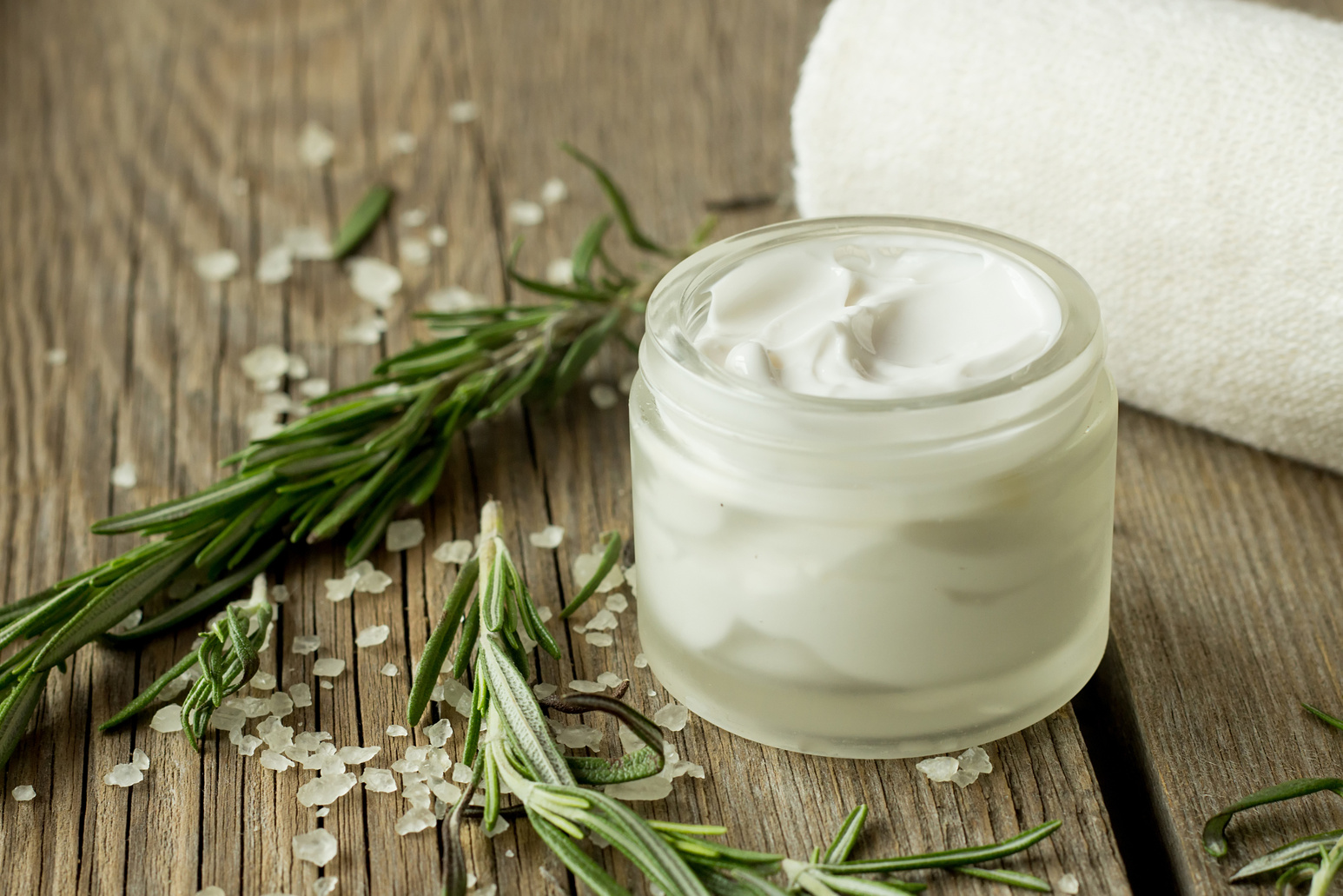 Face cream and rosemary on wooden table