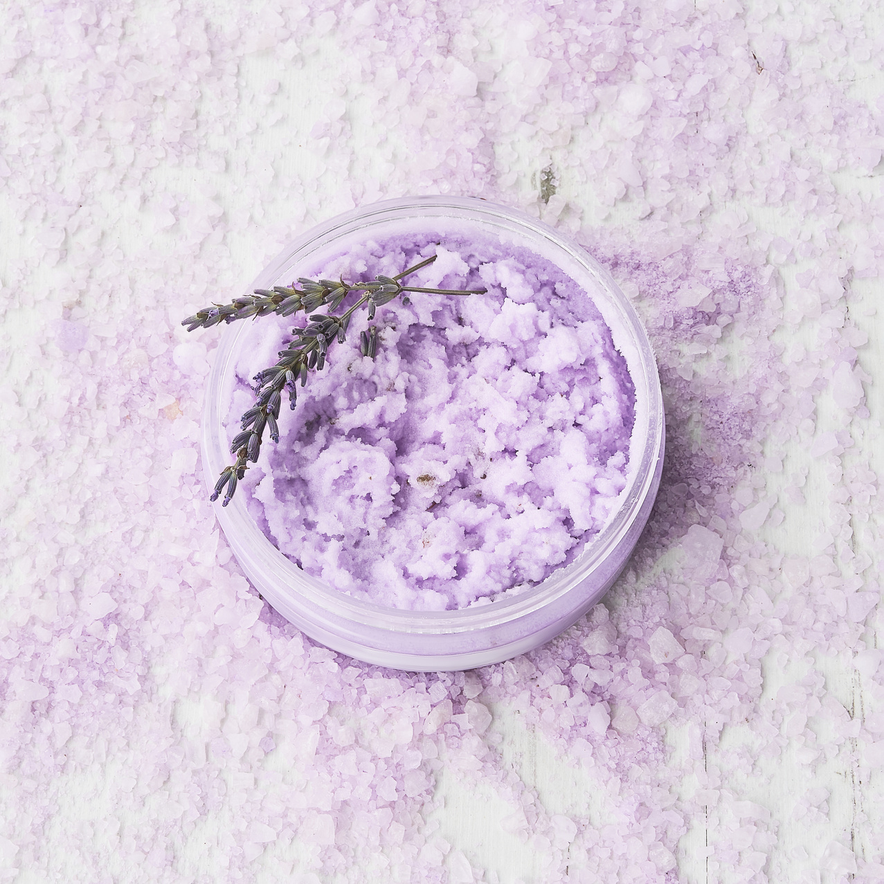Homemade lavender body scrub in a bowl on lavender bath salt background. Top view, copy space. SPA concept